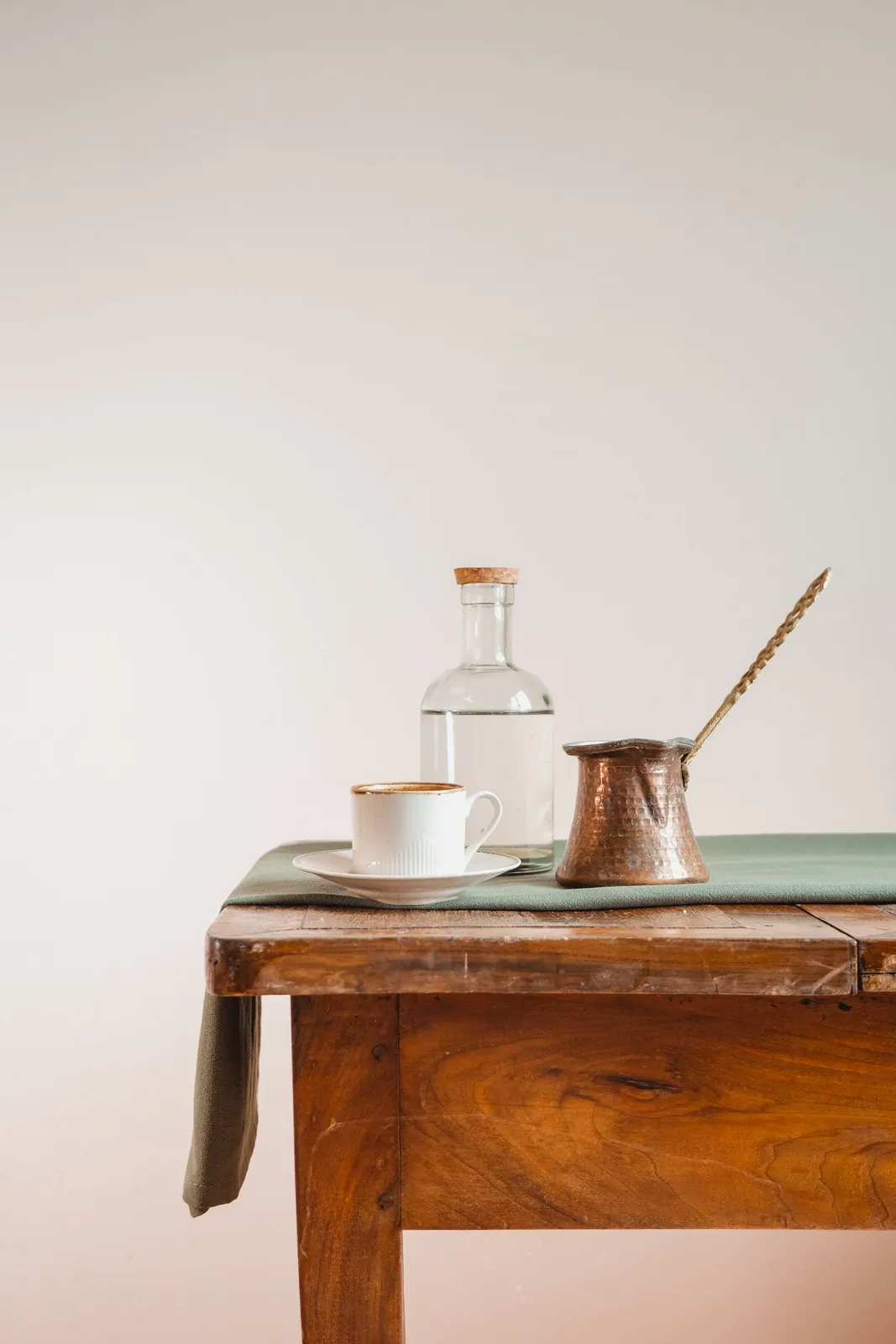 ركوة قهوة نحاسية وفنجان خزفي على طاولة خشبية